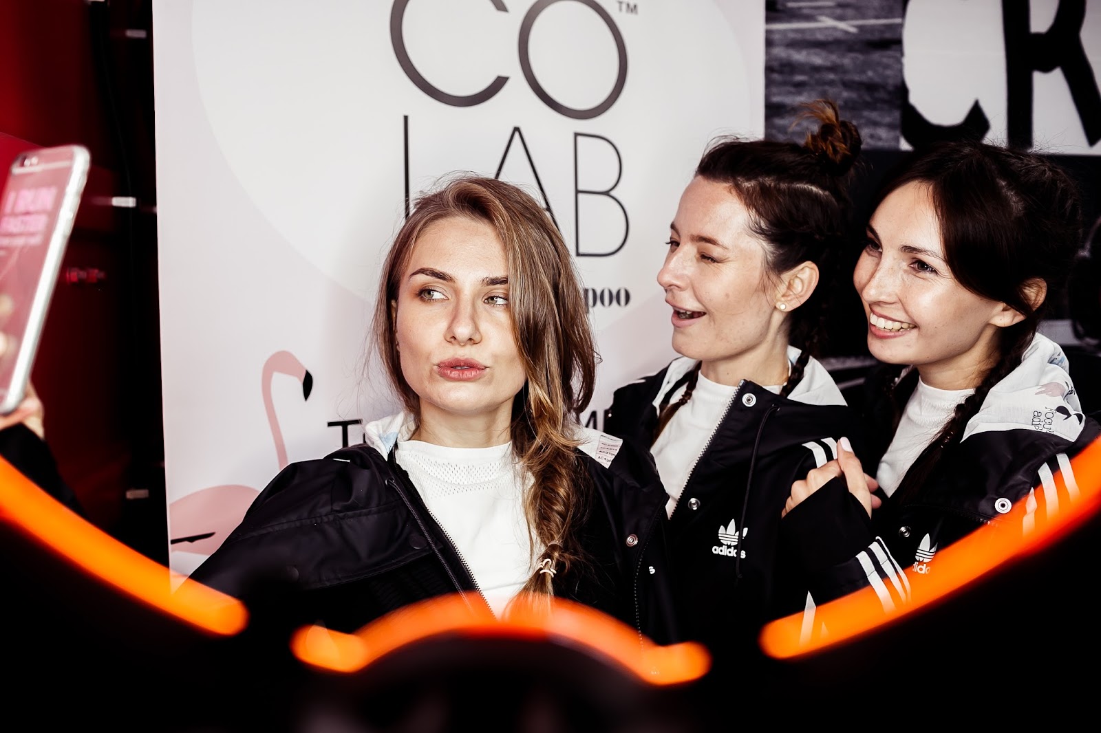 Три девушки делают селфи на мероприятии Co Lab в куртках adidas